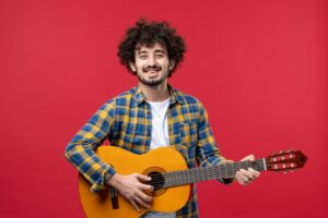 front-view-young-male-playing-guitar-red-wall-for music website